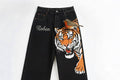 Black jeans with a tiger design on a white background

